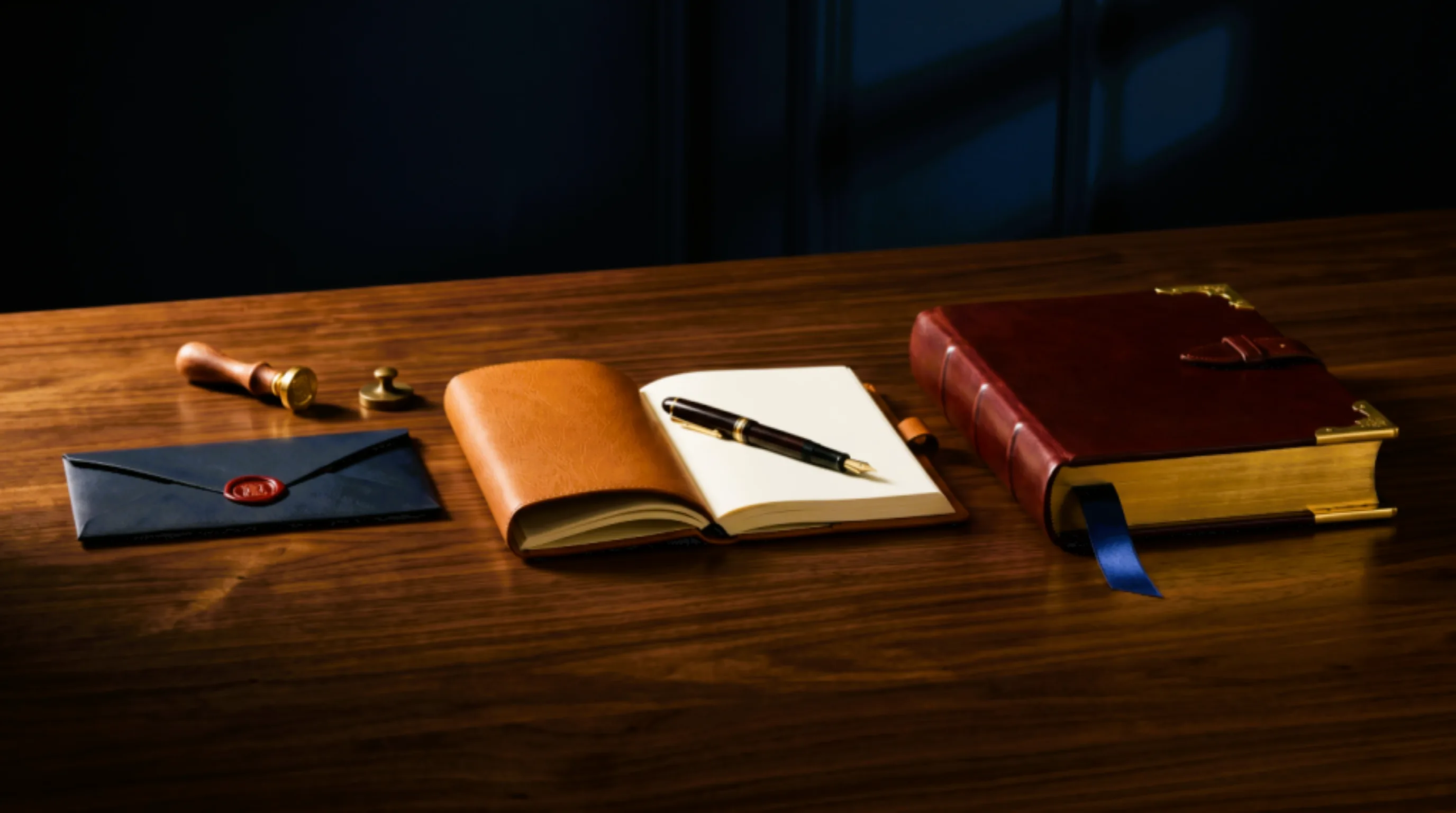 Three leather-bound documents of progressively greater thickness arranged on a polished walnut desk