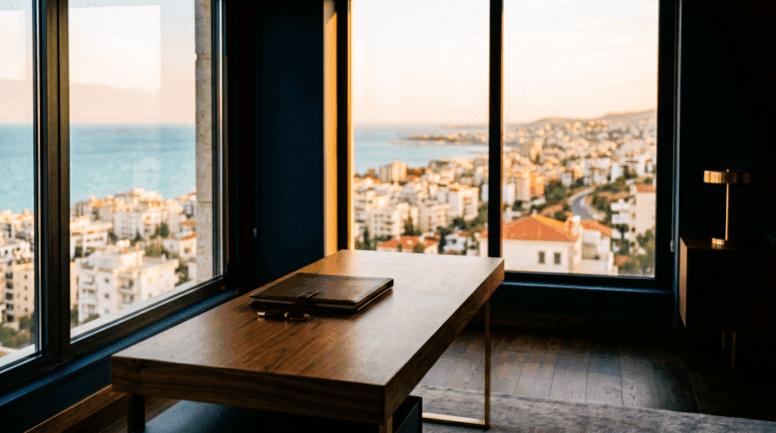 Executive office at golden hour overlooking a softly defocused Mediterranean coastal cityscape